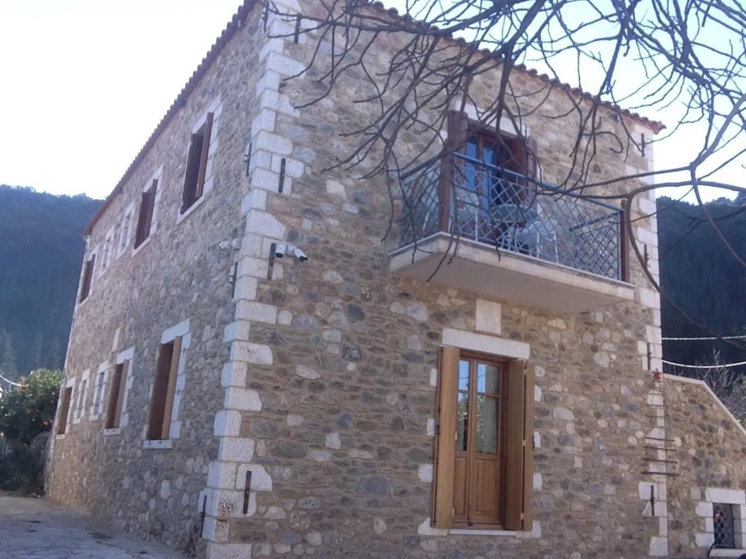 Πέτρινο διώροφο σπίτι με ξύλινη πόρτα και σιδερένιο μπαλκόνι